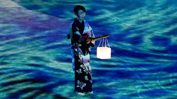 A performer holds a lantern during a moment of remembrance during the closing ceremony.