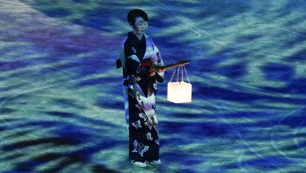A performer holds a lantern during a moment of remembrance during the closing ceremony.