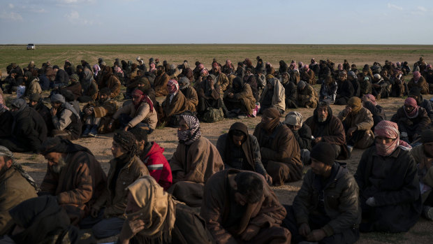 Men wait to be screened after being evacuated out of the last territory held by Islamic State militants, near Baghouz, eastern Syria.