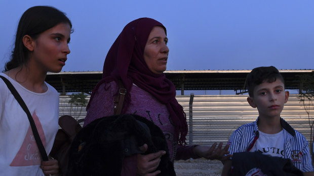 Najah (centre) with her daughter Solen (left) and her son Jowan (right) wait to be taken to their accommodation inside Bardarash refugee camp.