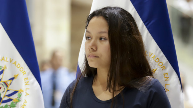 Tania Vanessa Avalos stands nearby as a government official speaks at a press conference at the airport after her arrival in San Salvador.