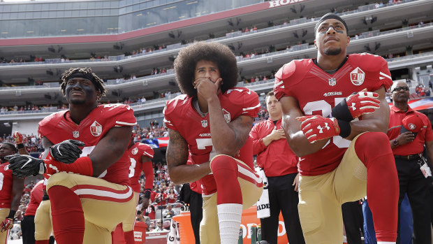 Iconic moment: Kaepernick, centre, takes a knee during the US national anthem in 2016.