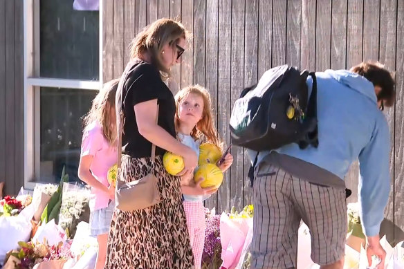 Jack Davey’s parents, Michael and Jayde, and his sisters look at the tributes and flowers left at Auburn South Primary School on Wednesday.