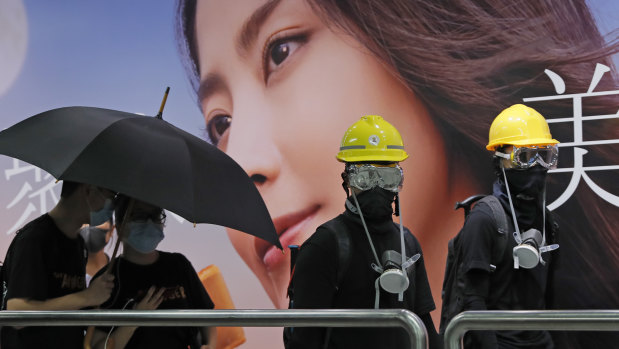 Demonstrators in Hong Kong moved en masse to a luxury shopping district Sunday evening after riot police used tear gas to clear out an area they were previously occupying.