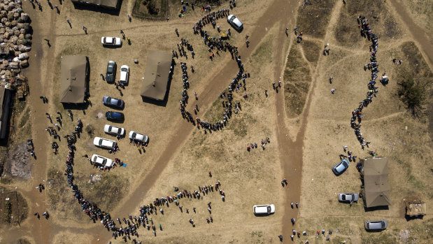 People wait in queues to cast their vote at a polling station in Harare.