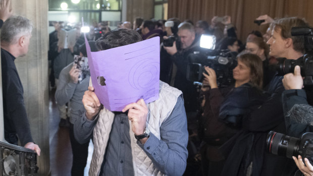 A defendant covers his face when arriving at the court in Berlin, Germany.