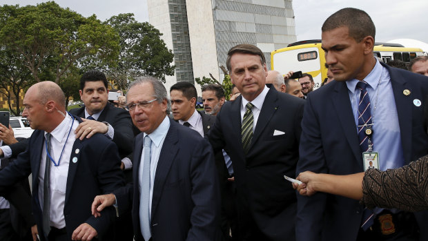 President Jair Bolsonaro, centre right, and Economy Minister Paulo Guedes, centre left, walk back to the presidential palace after a meeting.