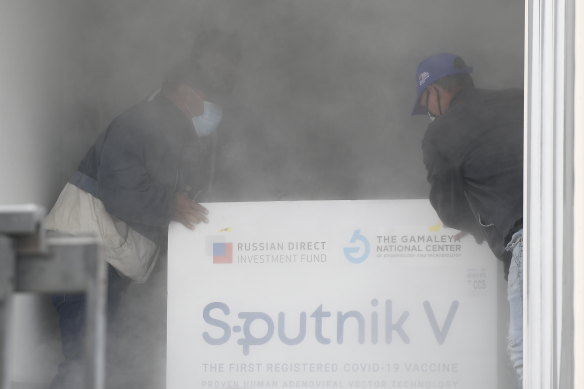 Workers place a box containing doses of the Russian COVID-19 vaccine Sputnik V into a refrigerated container after unloading it from a plane, at the Simon Bolivar International Airport in Maiquetia, Venezuela.