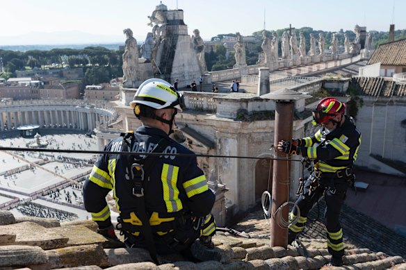 Members of the Vatican’s fire brigade attach the chimney to the roof of the Sistine Chapel.
