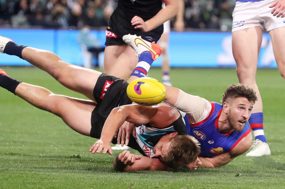 Ollie Wines of the Power is tackled by Marcus Bontempelli.