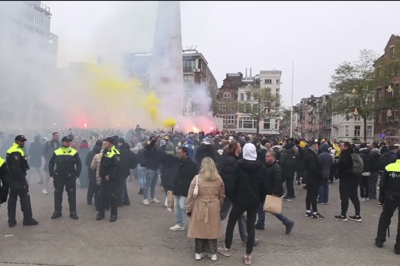 In this image taken from video, police stand guard as Maccabi Tel Aviv supporters light flares at the Dam square, in Amsterdam on Thursday.