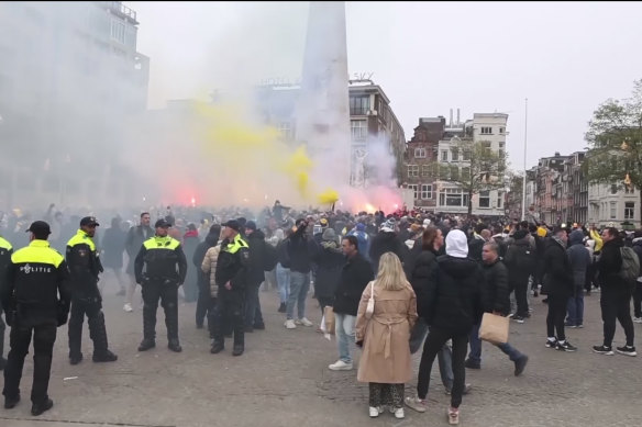 In this image taken from video, police stand guard as Maccabi Tel Aviv supporters light flares at the Dam square, in Amsterdam on Thursday.