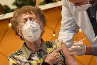 A resident of a nursing home reacts as she gets an injection of the COVID-19 vaccine.