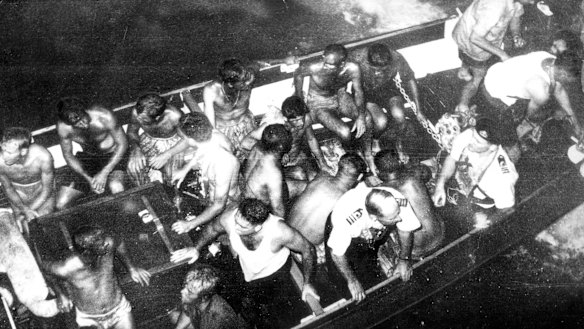 Survivors picked up by naval rescue craft prepare to board the aircraft carrier. 