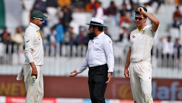 Umpire Aleem Dar talks with Nathan Lyon (left) and Pat Cummins.