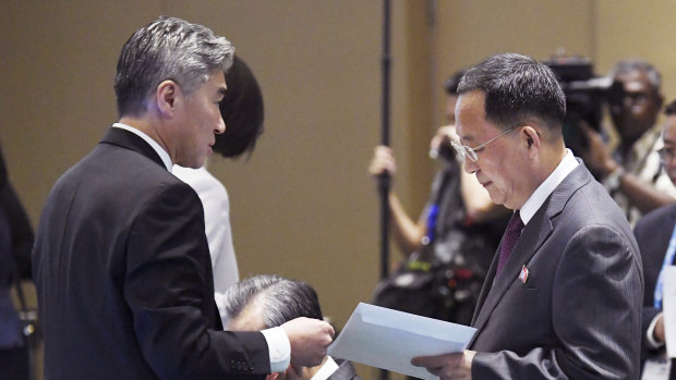 North Korean Foreign Minister Ri Yong Ho, right, receives an envelope from US Ambassador to the Philippines Sung Kim before the start of the 51st ASEAN Foreign Ministers Meeting in Singapore, on Saturday.