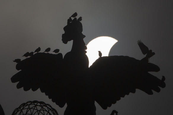 A partial solar eclipse moves behind a statue in Islamabad, Pakistan.