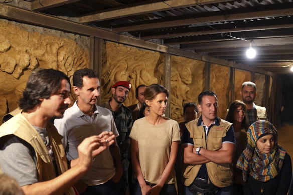 Bashar al-Assad, second left, and   Asma, centre, listen to a Syrian artist during their visit to one of the tunnels dug by rebels  in Jobar, near the Syrian capital Damascus, in 2018.   