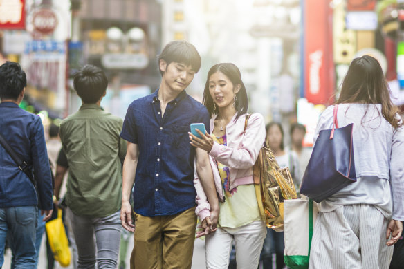 Young Japanese on a mobile phone game in Tokyo.