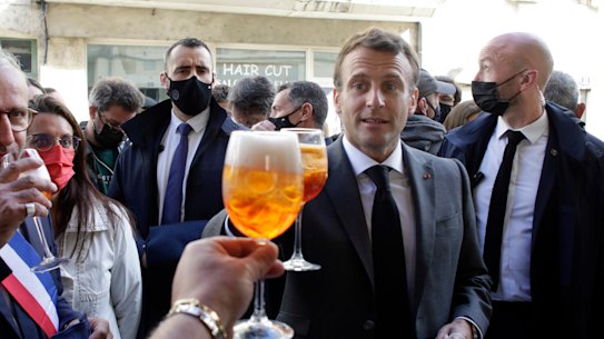French President Emmanuel Macron, right, and Nevers mayor Denis Thuriot, left, drink with shopkeepers during a visit to mark the reopening of cultural activities after closures during the COVID-19 pandemic, in Nevers, central France.