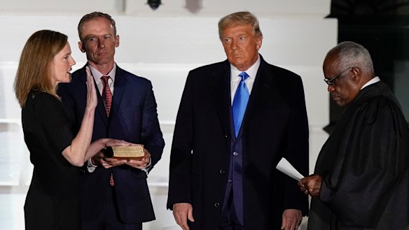 President Donald Trump watches as Supreme Court Justice Clarence Thomas administers the Constitutional Oath to Amy Coney Barrett at the White House in Washington, on Monday night (Tuesday AEDT).