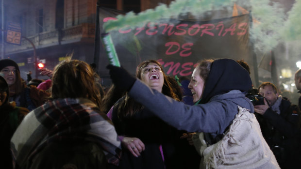 Women in support of decriminalising abortion, one spreading coloured smoke, gather outside Congress in Buenos Aires.