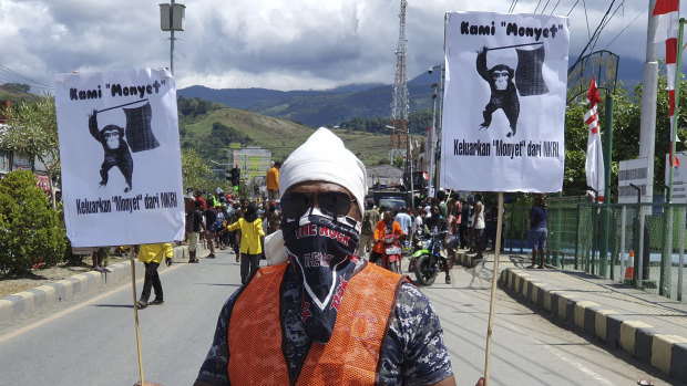 A protester holds posters that read "We are monkeys, monkeys want to be separated from Indonesia", during a rally in Abepura, Papua province, Indonesia. 