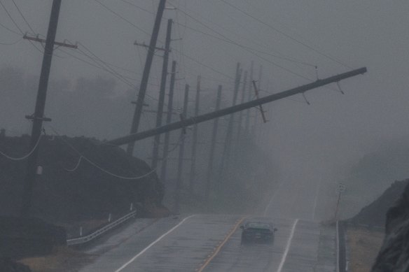 A vehicle drives near a downed utility pole dangling near Ocean View on the Big Island as Hurricane Lala lashed Hawaii.