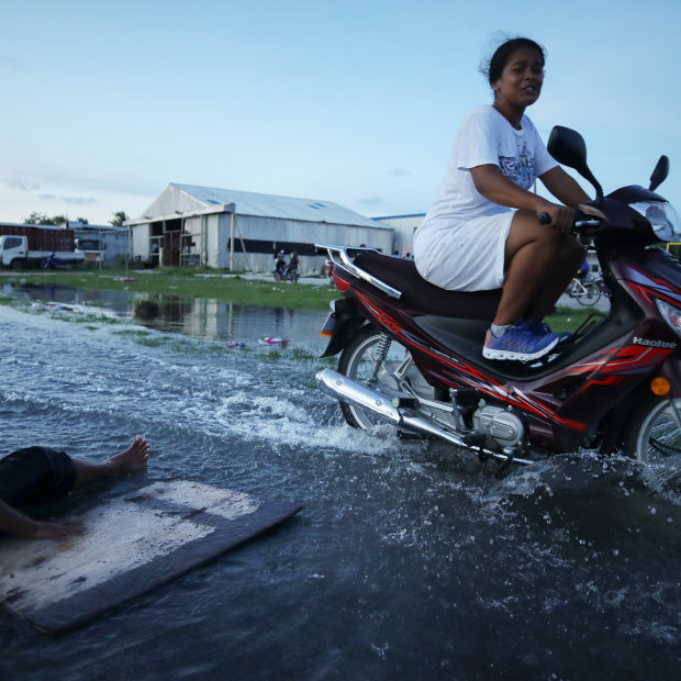 A woman rides her scooter through floodwater in Tuvalu’s capital, Funafuti, in November 2019.