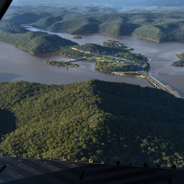 Floodwaters in the Hawkesbury River pass under Hawkesbury River Bridge at Mooney Mooney.