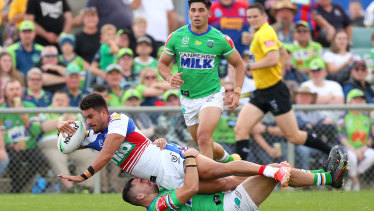 Enari Tuala of the Knights scores under pressure from Caleb Aekins.