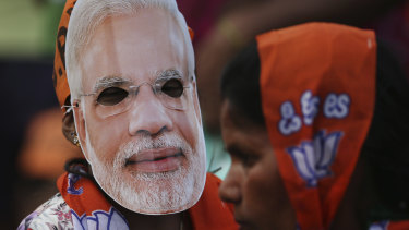 A girl wears a mask of Indian Prime Minister Narendra Modi during an election campaign rally in Bangalore, India.