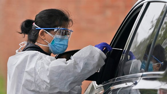 A member of a COVID-19 testing team prepares to administer a test at a testing site in Lawrence, New York.
