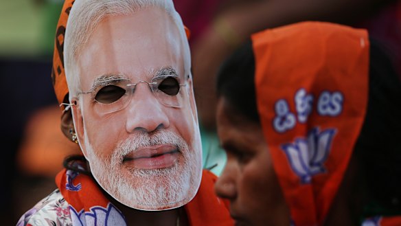 A girl wears a mask of Indian Prime Minister Narendra Modi during an election campaign rally in Bangalore, India.