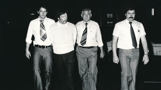 Peter Morgan (second from left) is led away by detectives after his arrest in April 1979. The guy on the far left appears to be wearing a tablecloth as a tie.