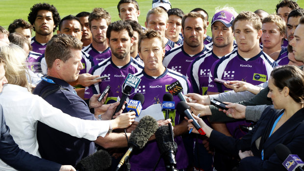 Solemn: Craig Bellamy speaks, surrounded by his players, in 2010 after the Storm were hammered by the NRL for cheating the salary cap.