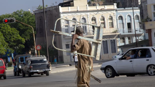 A worker carries scaffolding as he walks to a job in Havana. State employees are set to have a wage rise, part of upcoming economic reforms.