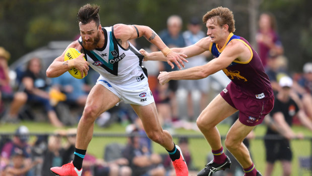 Powering on: Port Adelaide's Charlie Dixon (left) tries to brush off a tackle from Brisbane's Harris Andrews.
