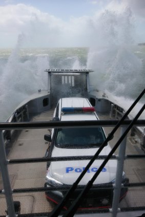 Queensland police vehicle copping a spray from Tropical Cyclone Oma on the way to North Stradbroke Island on Friday.