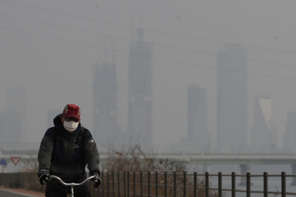 A man wearing a mask rides a bicycle along the Han river in Seoul, South Korea.