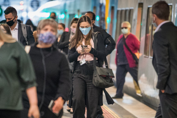 CBD workers wearing masks alight from a train at Southern Cross Station in 2021. 
