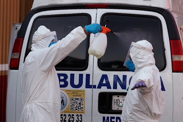 Ambulance workers disinfect each other after delivering a patient to the COVID-19 triage unit at Mexico General Hospital. 