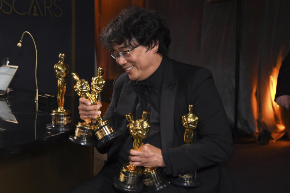 Backstage at the bar, Bong Joon-ho holds the Oscars for best original screenplay, best international feature film, best directing, and best picture for Parasite.