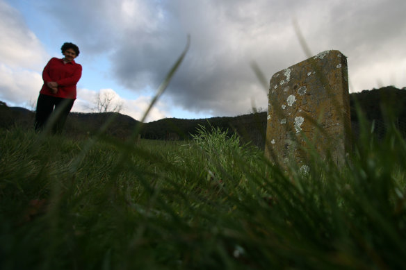 Eva Park, a descendant of Ah Sue, a Chinese resident of the Buckland Valley, stands by one of three graves of Chinese victims of the 1857 riot near Bright.