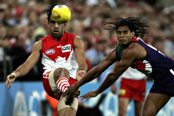 Adam Goodes passes the ball despite the attention of Docker Troy Cook.