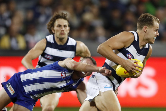 Jake Kolodjashnij of the Cats is tackled by North Melbourne’s Jack Mahony during their clash at GMHBA Stadium. 