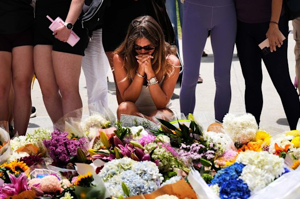 A woman kneels and prays at a flower memorial to shooting victims outside the Bondi Pavilion on Monday, December 15.