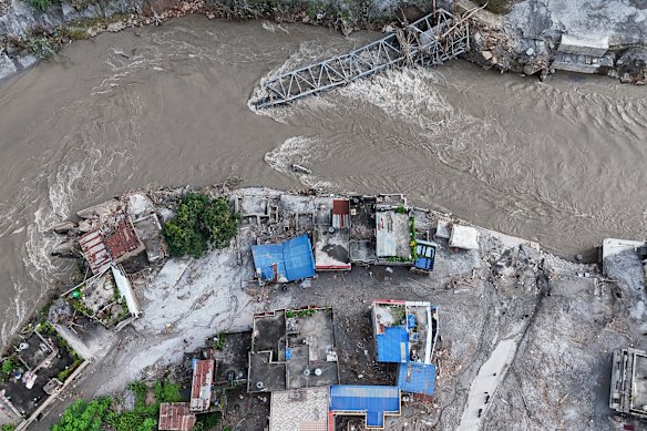 A collapsed bridge, debris and mud covering an area following flash floods in DeviGhat village, Nepal.