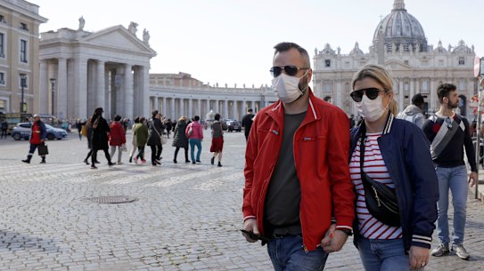 A couple wearing face masks stroll outside St. Peter's Square.