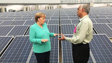 German Chancellor Angela Merkel speaks with an officer as she looks at solar panels on the roof of a metro station in New Delhi, India.